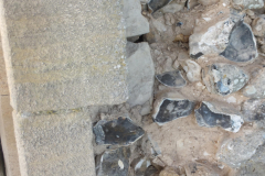 The lime mortar of the tower behind the outer layer of cement has failed, so this shows an area that needs to be rebuilt